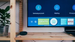 Czarny telewizor na brązowej drewnianej półce obok głośnika Google Home w salonie
